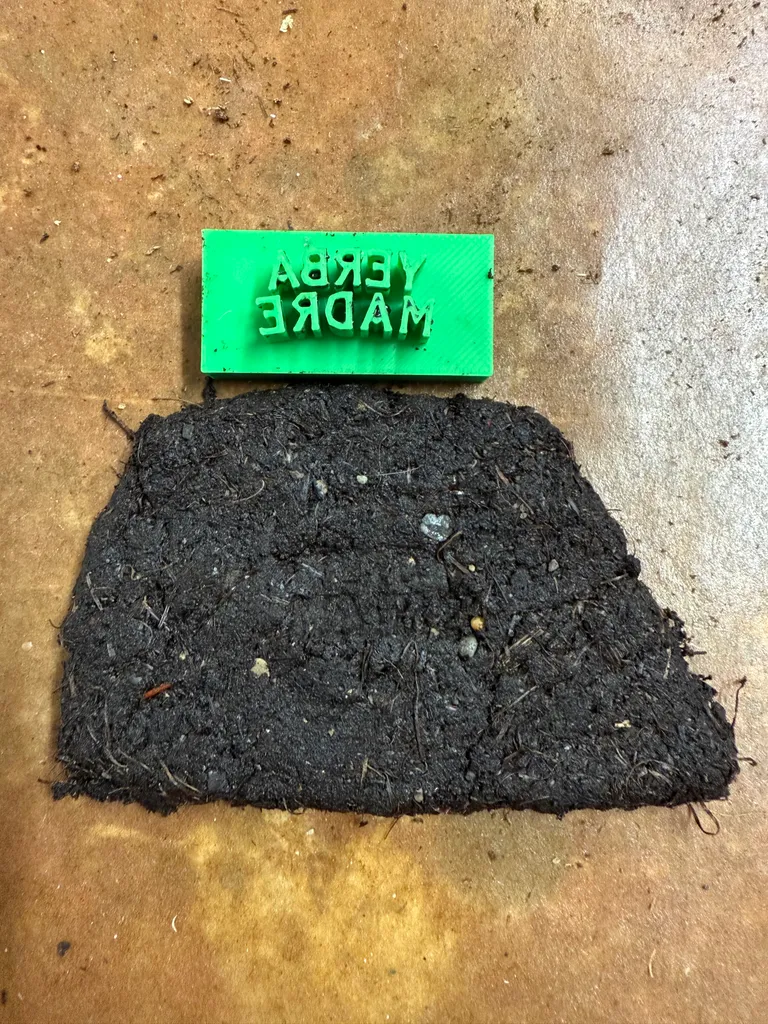 A 3D printed Yerba Madre stamp next to a pressed dirt panel