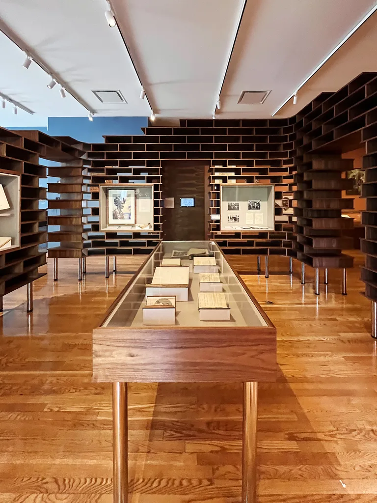 Long walnut display case with an acrylic vitrine in front of the curved wall