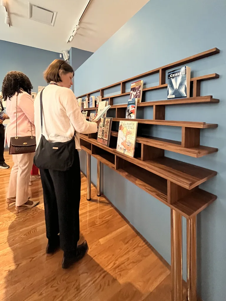 Wall-mounted walnut display shelf with visitors on opening day